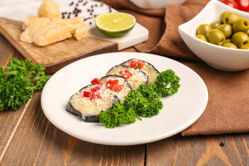 Fototapeta na wymiar Plate with tasty baked Eggplant Parmesan on wooden background
