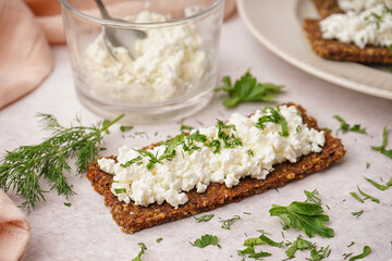 Tasty cottage cheese and rye bread on light grunge background