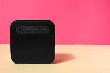 Modern square speaker on color background