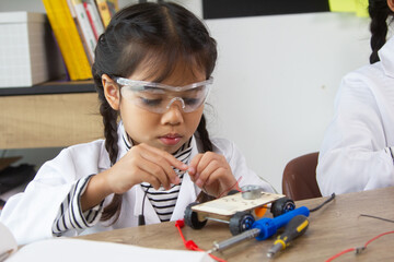 School student making robotic cars. Girl at robotics school makes robot managed from the constructor, child learns robot constructing.