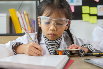 School student making robotic cars. Girl at robotics school makes robot managed from the constructor, child learns robot constructing.