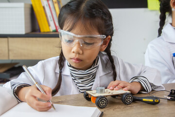 School student making robotic cars. Girl at robotics school makes robot managed from the constructor, child learns robot constructing.