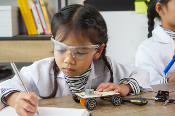 School student making robotic cars. Girl at robotics school makes robot managed from the constructor, child learns robot constructing.