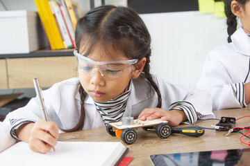 School student making robotic cars. Girl at robotics school makes robot managed from the constructor, child learns robot constructing.