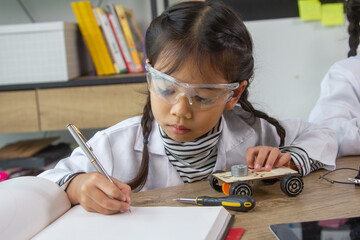School student making robotic cars. Girl at robotics school makes robot managed from the constructor, child learns robot constructing.