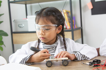 School student making robotic cars. Girl at robotics school makes robot managed from the constructor, child learns robot constructing.