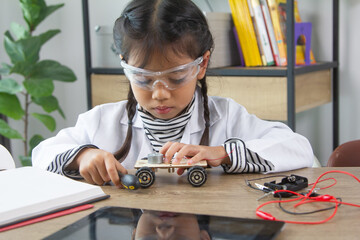 School student making robotic cars. Girl at robotics school makes robot managed from the constructor, child learns robot constructing.