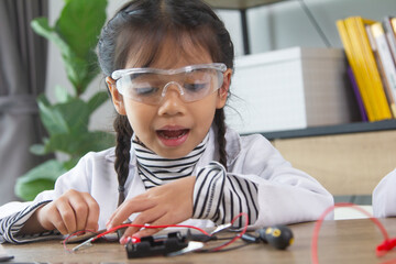 School student making robotic cars. Girl at robotics school makes robot managed from the constructor, child learns robot constructing.