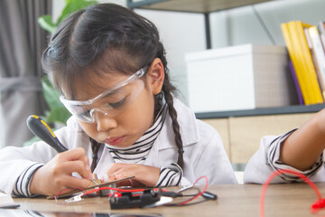 School student making robotic cars. Girl at robotics school makes robot managed from the constructor, child learns robot constructing.