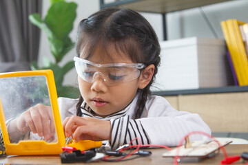 School student making robotic cars. Girl at robotics school makes robot managed from the constructor, child learns robot constructing.