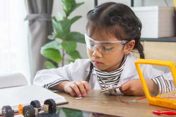 School student making robotic cars. Girl at robotics school makes robot managed from the constructor, child learns robot constructing.
