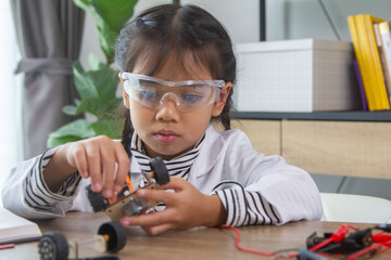 School student making robotic cars. Girl at robotics school makes robot managed from the constructor, child learns robot constructing.