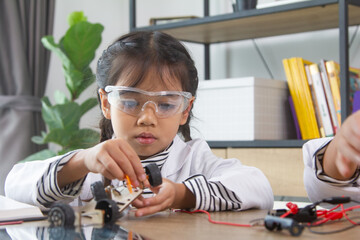 School student making robotic cars. Girl at robotics school makes robot managed from the constructor, child learns robot constructing.