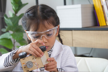 School student making robotic cars. Girl at robotics school makes robot managed from the constructor, child learns robot constructing.