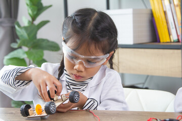 School student making robotic cars. Girl at robotics school makes robot managed from the constructor, child learns robot constructing.