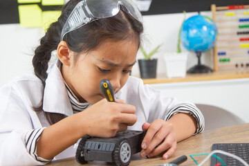 School student making robotic cars. Girl at robotics school makes robot managed from the constructor, child learns robot constructing.