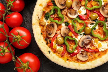 Vegetable pizza with ingredients on dark background