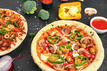 Vegetables pizzas with ingredients and sauces on dark background