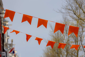 Colourful of King’s Day (in Dutch: Koningsdag) Selective focus of pennant orange flags hanging...