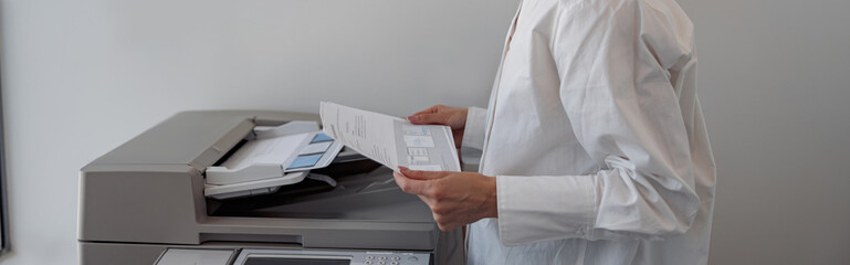 Focused woman worker scanning document on photocopy machine In modern office. Blurred background