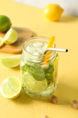 Mason jar of tasty mojito on yellow background
