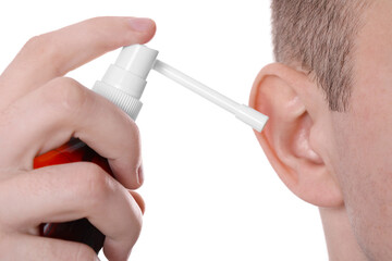 Man using ear spray on white background, closeup