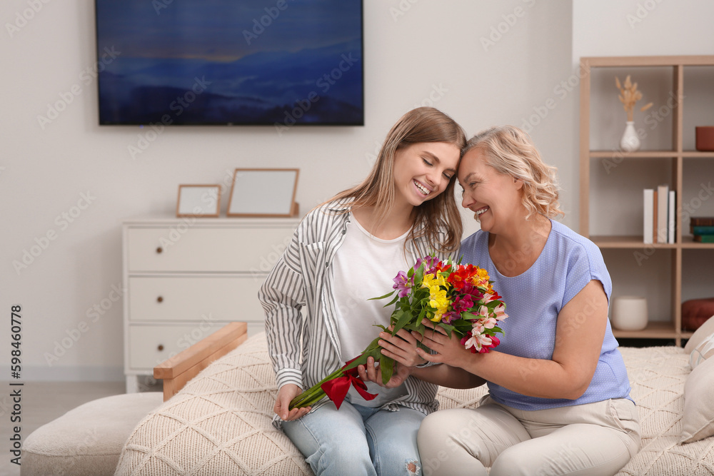 Poster Young daughter congratulating her mom with flowers at home. Happy Mother's Day