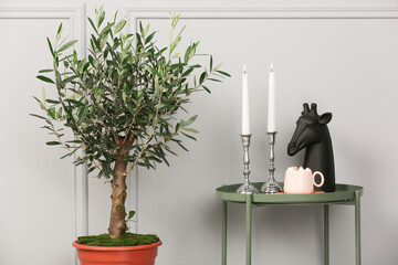 Table with fancy decor elements, marshmallow cocoa and beautiful young potted olive tree near grey...