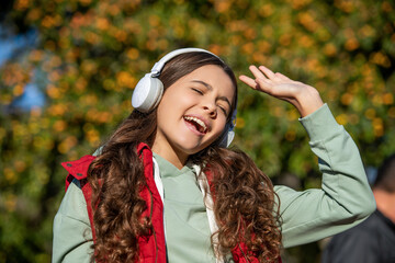 photo of teen girl singing and listening music. teen girl listening music outdoor.