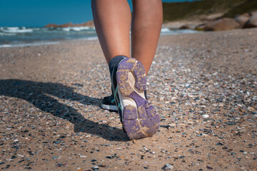 Detalhe dos pés de uma pessoa caminhando sobre conchinhas na praia