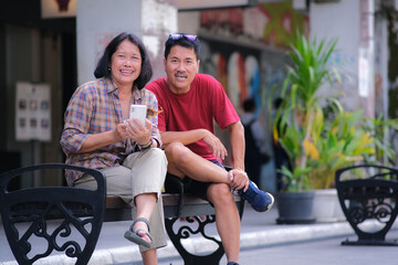 Asian man and woman sitting together on a park bench on the road side of Malioboro street