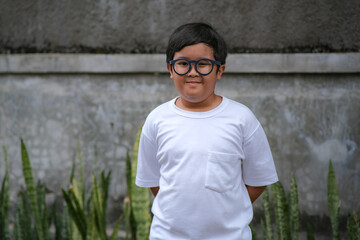 An Asian boy standing alone and wearing glasses due to too much playing video games © Simon