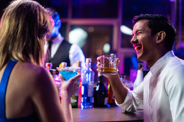 Beautiful young couple having fun, drinking alcohol cocktail in a bar. 