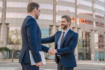 smiling two business men in suit are handshaking in agreement. photo of two business men