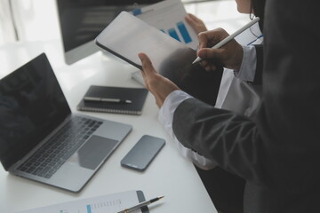 Group of confident business people point to graphs and charts to analyze market data, balance sheet, account, net profit to plan new sales strategies to increase production capacity.