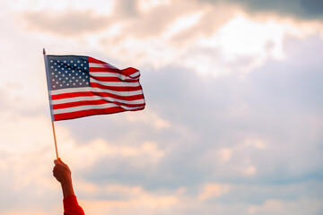 Hand Waving the Flag of the United Stated of America. Optimistic person holding American flag celebrating citizenship
 - obrazy, fototapety, plakaty