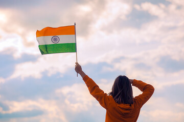 Woman Waving Indian Flag Looking at the Sky. Indian girl holding national flag celebrating August...