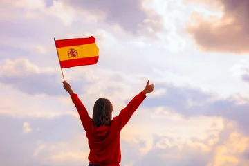 Foto op Canvas Woman Waving Spanish Flag Looking at the Sky. Optimistic girl holding national flag celebrating citizenship  © nicoletaionescu