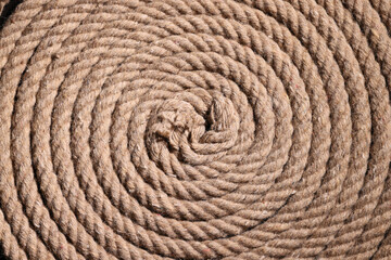 Fototapeta na wymiar Coil of twisted strong brown rope as background texture