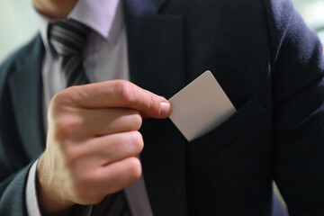 Businessman in suit takes credit card out of jacket pocket