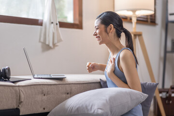 Beautiful Young Asian woman using laptop computer on sofa at home, shopping online with internet in happy mood and Relax part time concept
