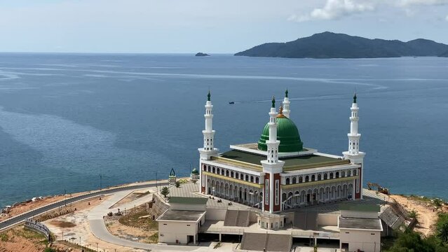 Baitul Makmur Great Mosque, Tarempa. Top aerial view of the magnificent beautiful mosque building with white paint and green dome with blue sea background. Eid al-Fitr Eid al-Adha. 4k Video Footage.