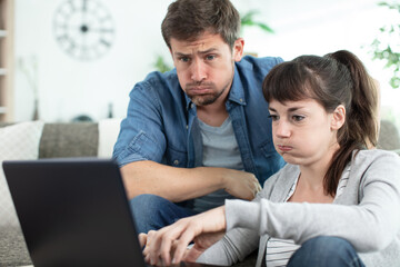 couple calculating their domestic budget with stressed and frustrated looks