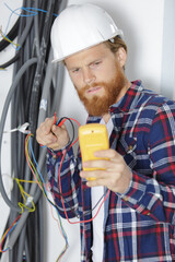 an electrician measuring voltage of cables