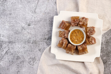 Aspic or jellied meat on a plate with mustard on a dark grey background. Top view, flat lay
