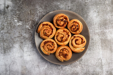 Homemade Savory Bacon Onion Rolls on a round plate on a dark background. Top view, flat lay