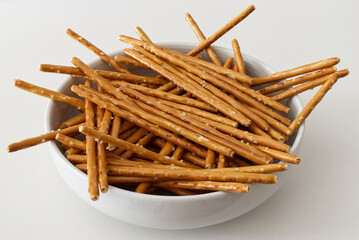 Salted pretzel sticks in a bowl isolated on white background