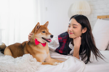 Beautiful asian woman eyes sparkled with joy as she watched her furry companion in bedroom.