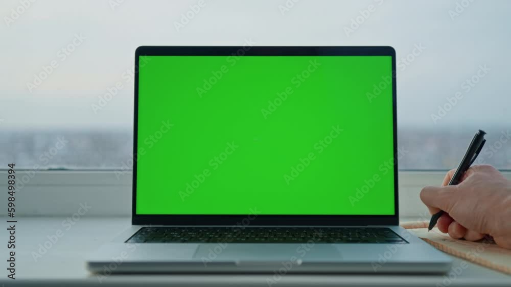 Aufkleber man writing in notebook near laptop with green screen workplace with big window at home or office Generative AI