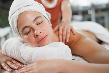 Fototapeta na wymiar Beautiful caucasian woman having shoulder massage at night spa salon 